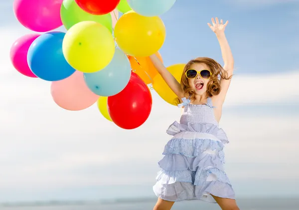 Счастливая девушка прыжки с красочными воздушными шарами — стоковое фото