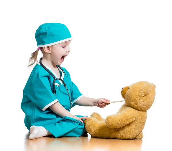 Восхитительный ребенок оделся как доктор, играющий с игрушкой по белому — стоковое фото