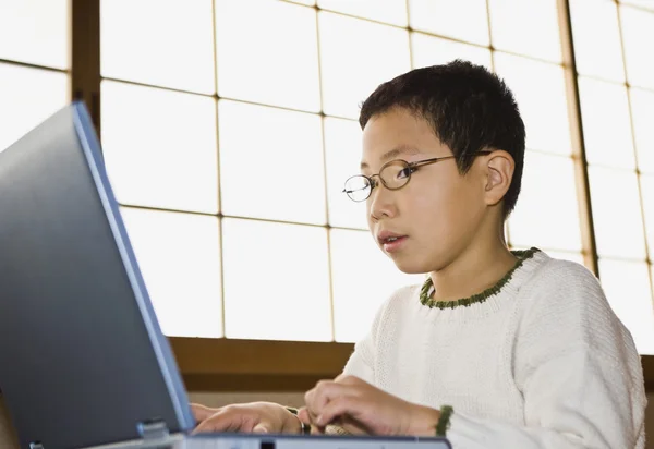 Азиатские мальчик, набрав на ноутбуке — стоковое фото