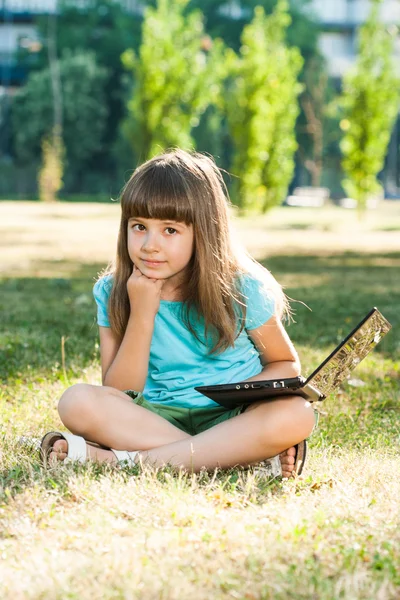 Красивая девочка, сидя в парке с ее ноутбуком — стоковое фото
