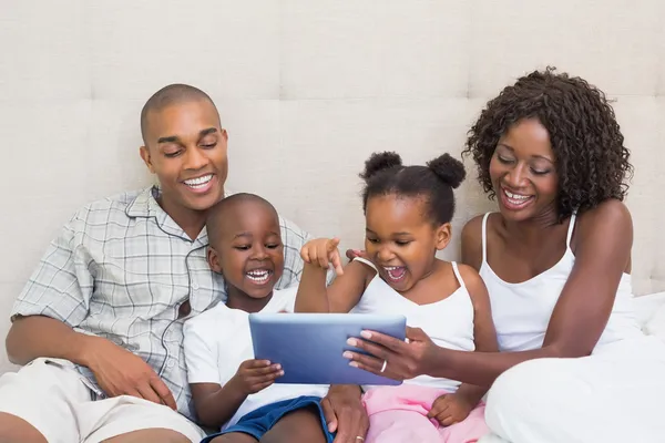 Счастливая семья, с помощью планшета вместе на кровати — стоковое фото
