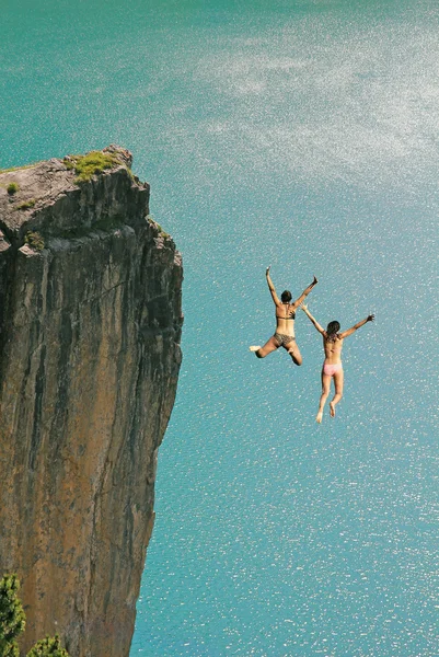 Две девочки прыжки Клифф, против бирюзовый океан — стоковое фото
