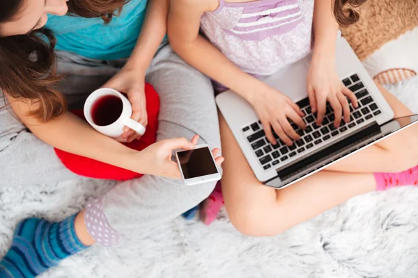 Девочки, используя ноутбук и пустой экран мобильный телефон дома — стоковое фото