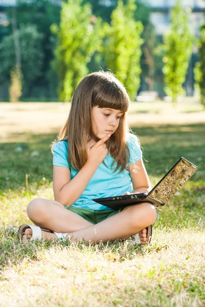 Красивая девочка, сидя в парке с ее ноутбуком — стоковое фото