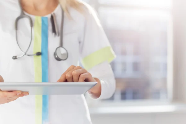 Женщина-врач, использующая планшетный компьютер в больнице — стоковое фото