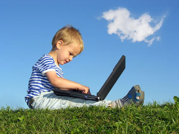Ребенок с ноутбуком сидеть голубое небо с облаком — стоковое фото